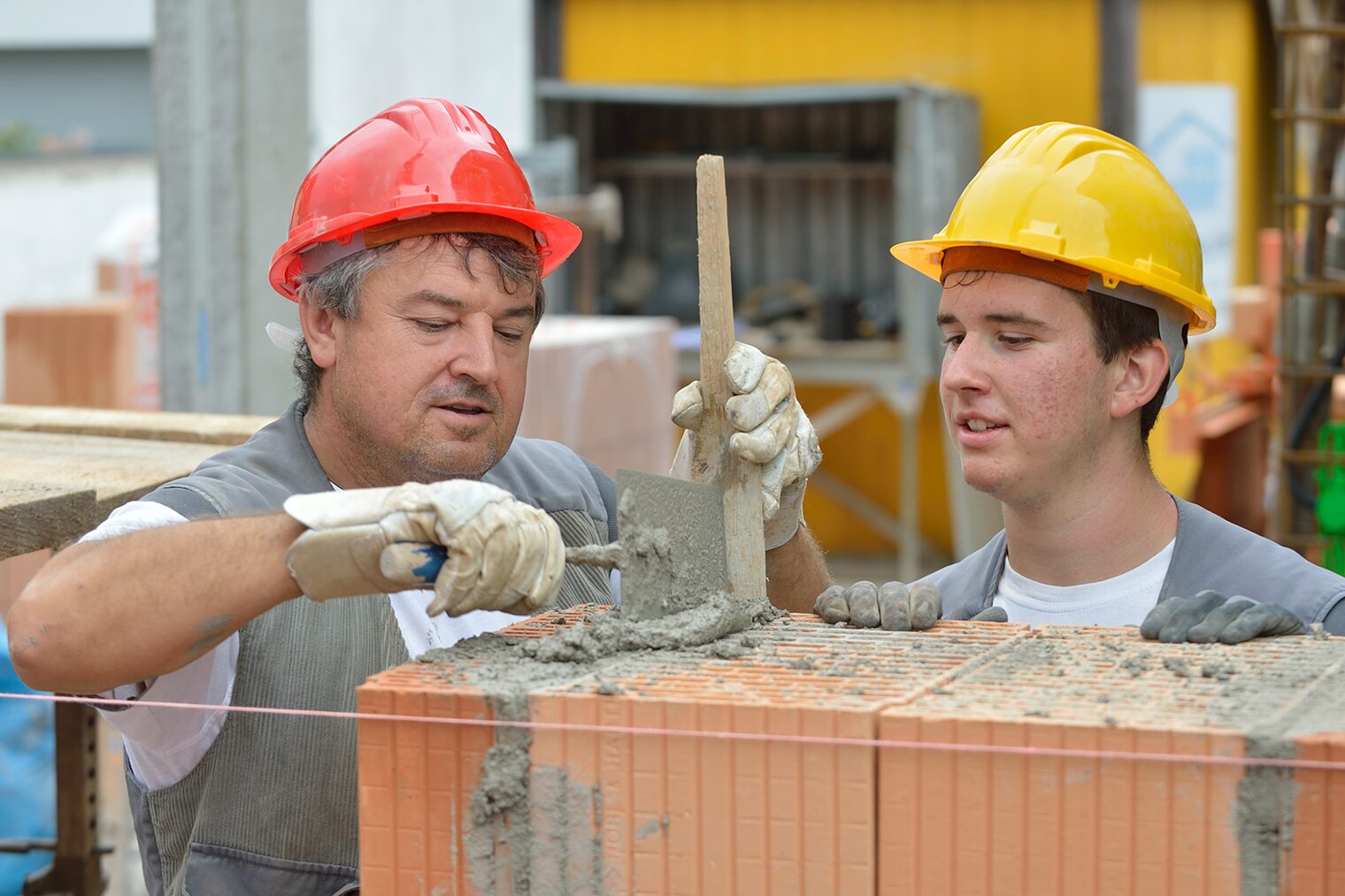 Praktikum im Handwerk Ein Maurermeister mit einem Praktikanten auf einer Baustelle.