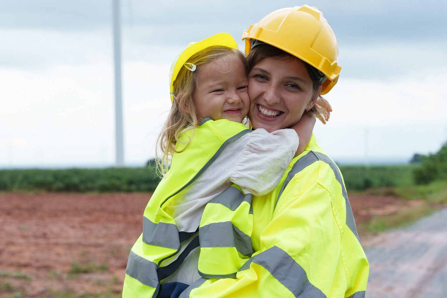 Mutterschaft im Handwerk Eine Mutter mit Kind in Warnwesten auf einer Baustelle.