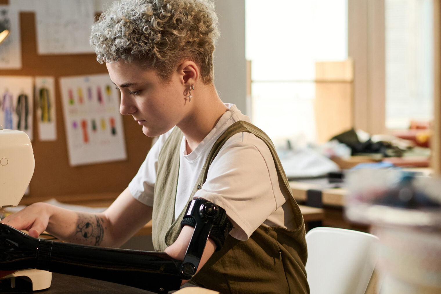 Inklusion im Handwerk Eine Schneiderin mit Armprothese näht ein Kleidungsstück mit einer Nähmaschine.