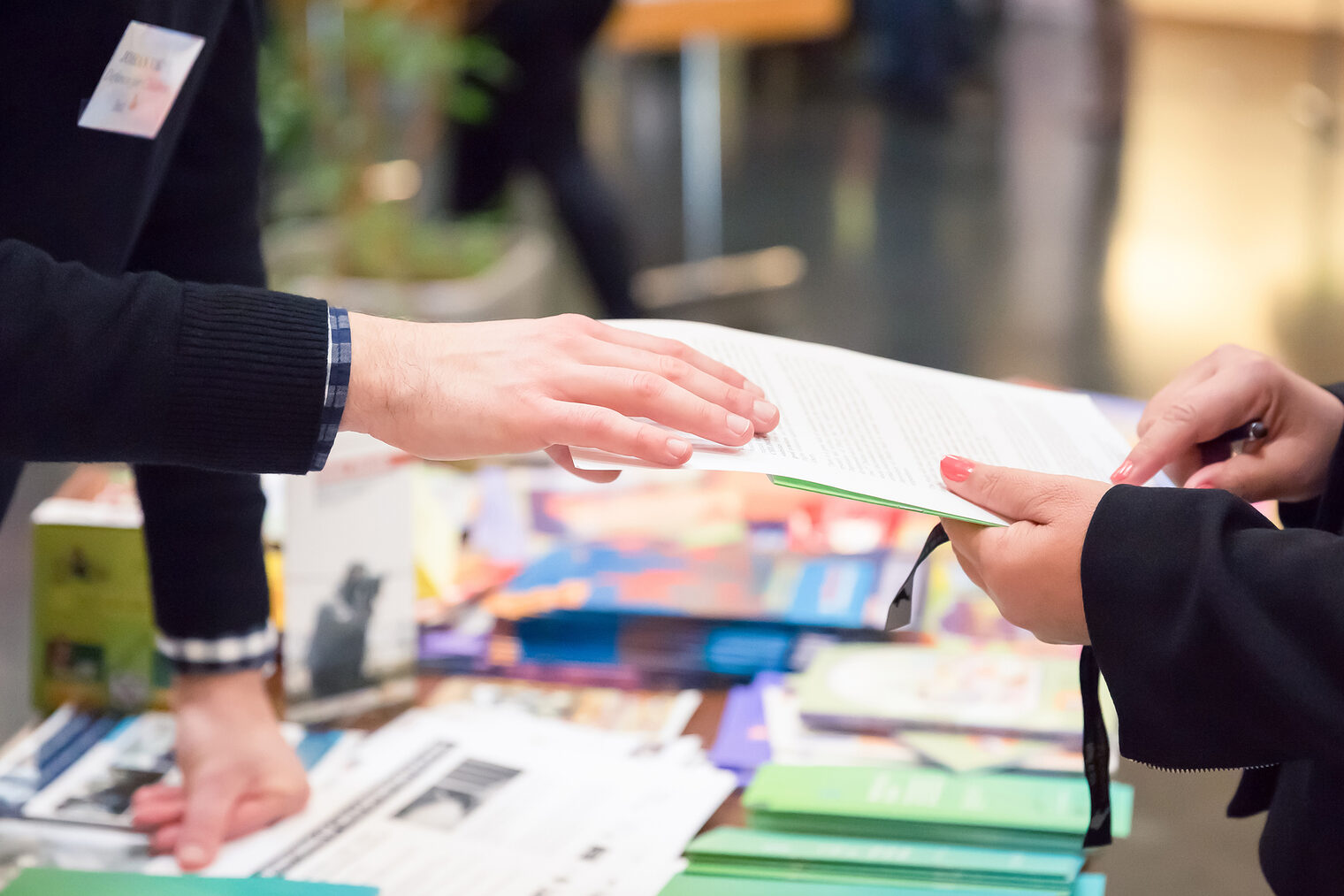 Fachmesse Ein Mann reicht einer Frau ein Informationsblatt auf einer Fachmesse.